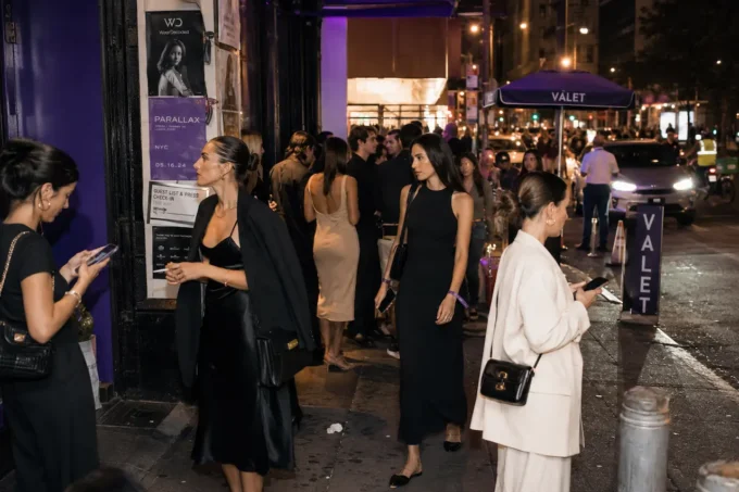 Fashionable guests arriving at a modern evening event wearing relaxed influencer-style dresses outside a busy urban venue.