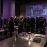 Fashion industry professionals networking inside a contemporary gallery space with subtle violet installations and editorial WearDecoded branding.