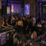 Fashion and music event inside a modern industrial rooftop venue with DJs, stylish guests, and relaxed creative atmosphere.