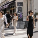 Street-style fashion scene featuring women wearing relaxed minimalist dress trends popular among influencers in a bright urban setting.