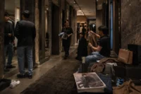 Luxury fashion store fitting room corridor with shoppers trying on clothing in a warm cinematic retail environment.